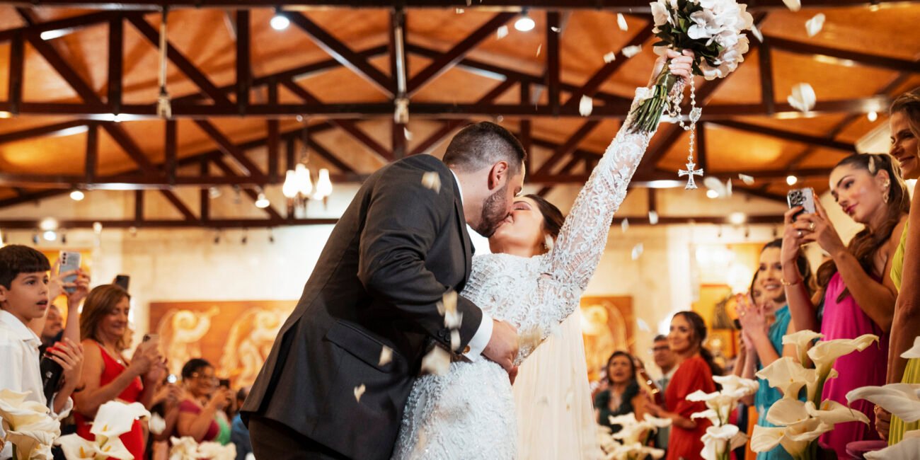 Casamento na Igreja São João Eudes: Jéssica ergue o buquê e beija Ramiro sob as pétalas.