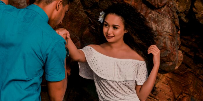 A mão levantada Júnior segura a mão levantada de Vandressa, que sorri diante da pedra.